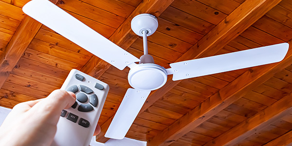 Person Controlling White Ceiling Fan With Remote