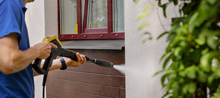 A homeowner power washing the exterior of their home. 