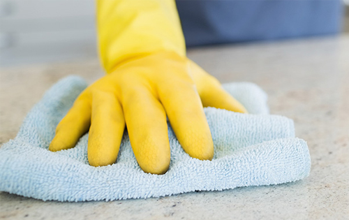 Homeowner Wearing Yellow Gloves Wiping Countertop With Rag