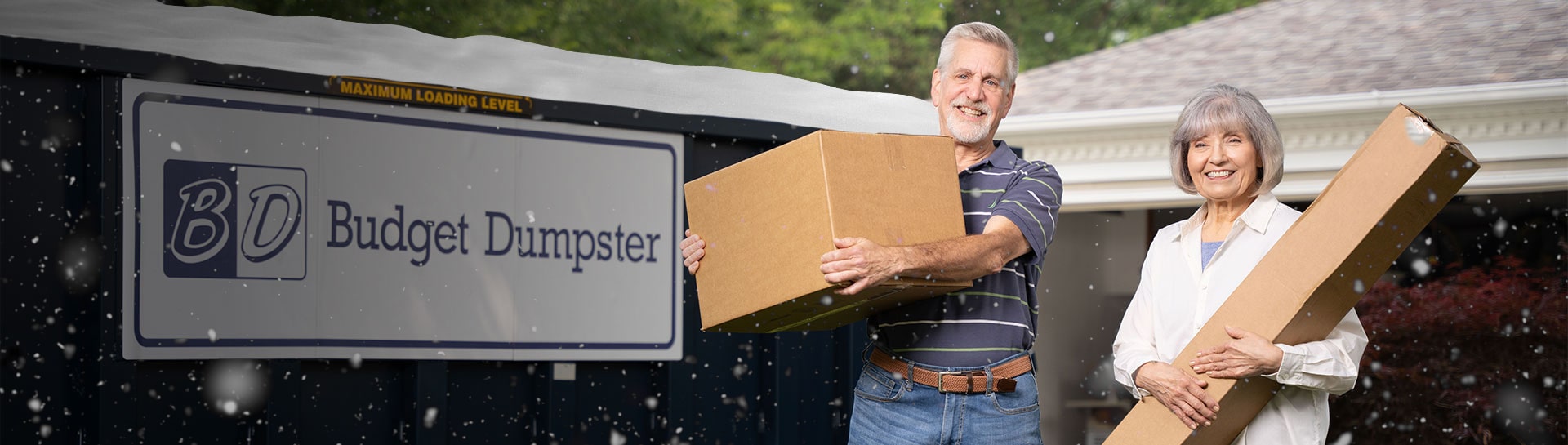 Couple Holding Boxes in Front of a Blue Budget Dumpster